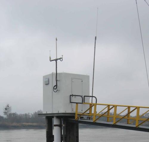 Local préfabiqué entouré d'eau. Puit et antennes visibles